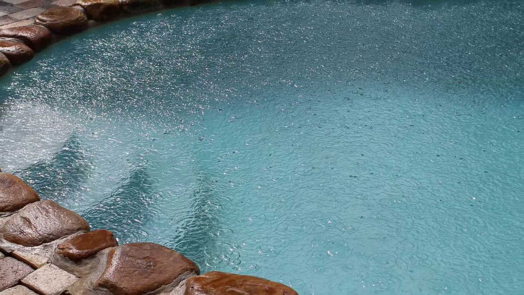 Close detail of pool water and stone coping from the air